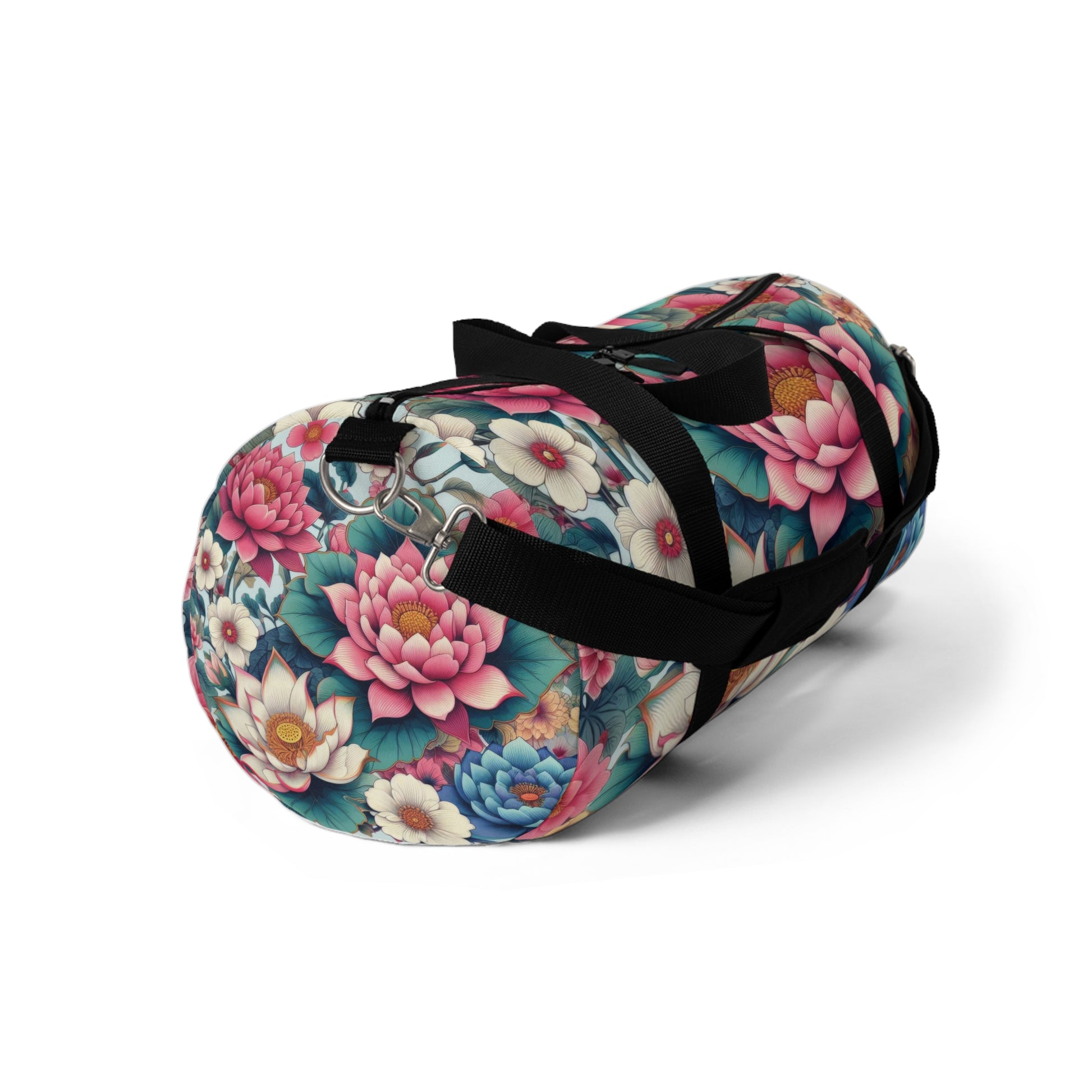 A duffel bag with a vibrant floral pattern featuring large blooms in shades of pink, blue, and white, with green foliage, all set against a dark background. The bag has a black adjustable shoulder strap and black zippers.