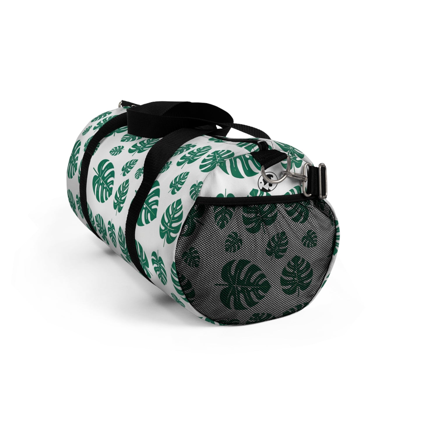 The image shows a cylindrical duffel bag patterned with green tropical leaves and equipped with a black shoulder strap