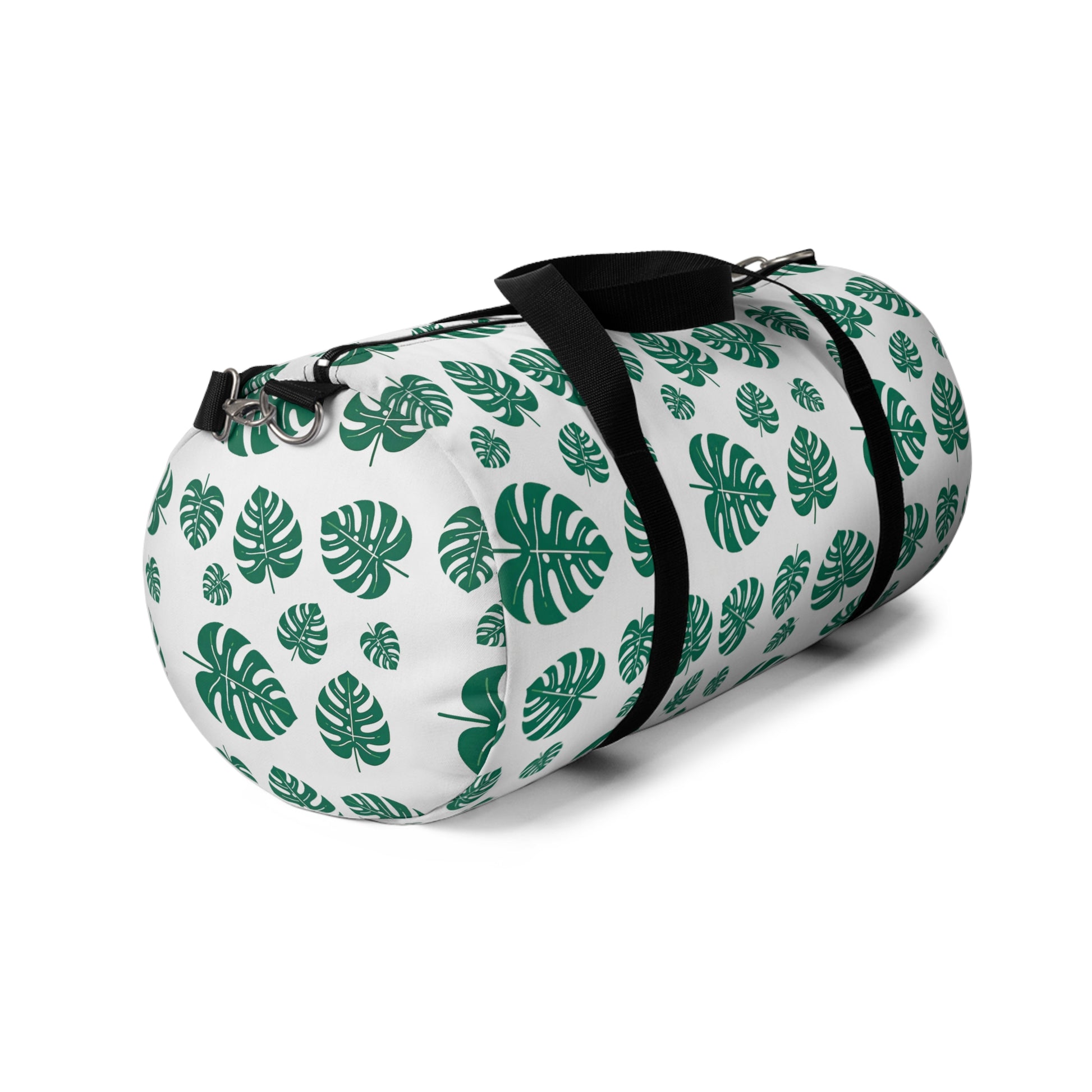 The image shows a cylindrical duffel bag patterned with green tropical leaves and equipped with a black shoulder strap