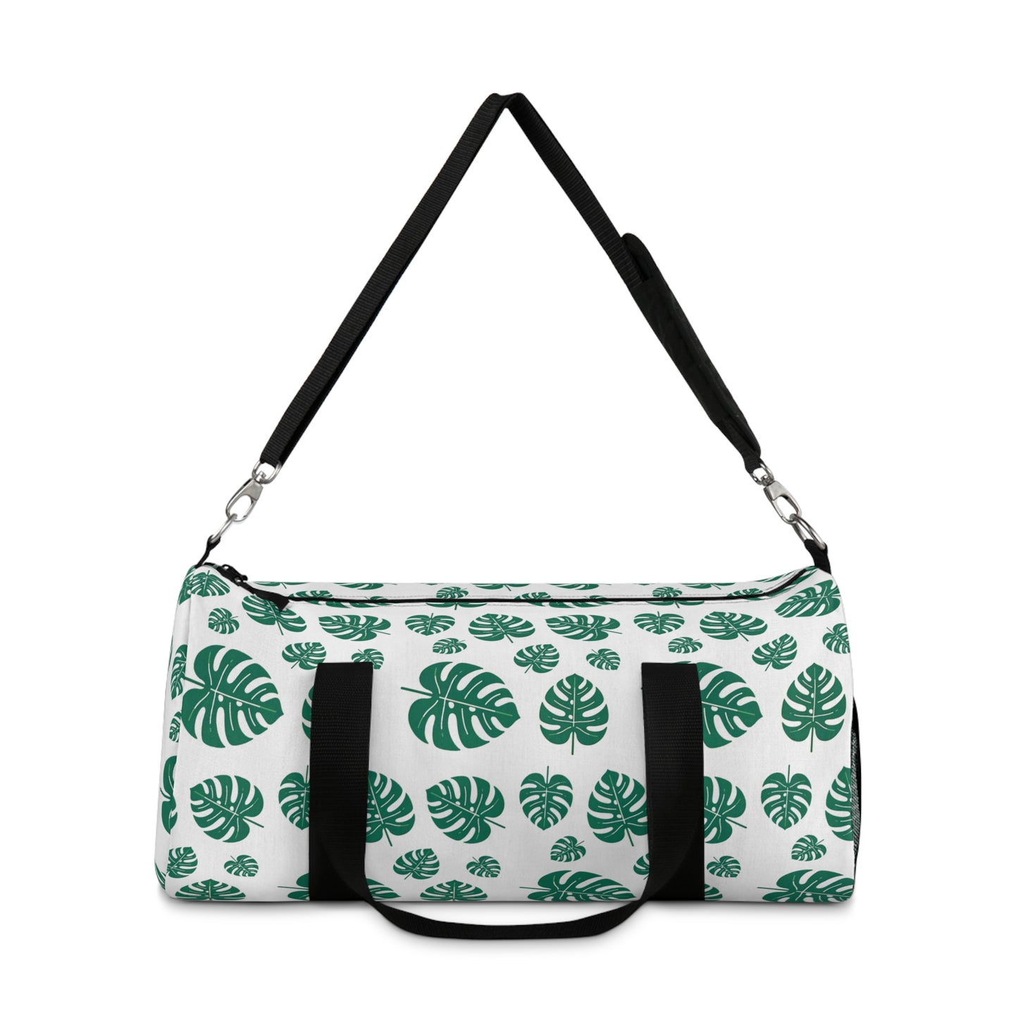 The image shows a cylindrical duffel bag patterned with green tropical leaves and equipped with a black shoulder strap